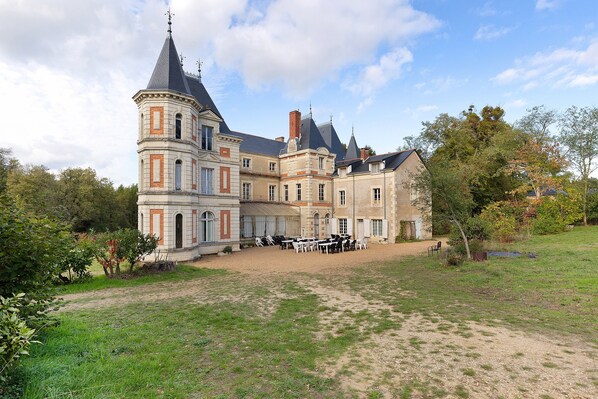 A large, historic building with multiple towers and a courtyard with outdoor seating.