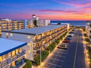 A hotel with multiple floors, outdoor seating, and a view of the ocean at sunset. - Oceanside 1BR Condo Close to Beach (Ocean City)