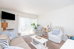 A living room with a sofa, armchairs, a coffee table, and a television. - Oceanside 1BR Condo Close to Beach (Ocean City)