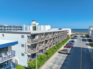 Un hotel de diversos pisos amb balcons, un pàrquing i vista a l'oceà.