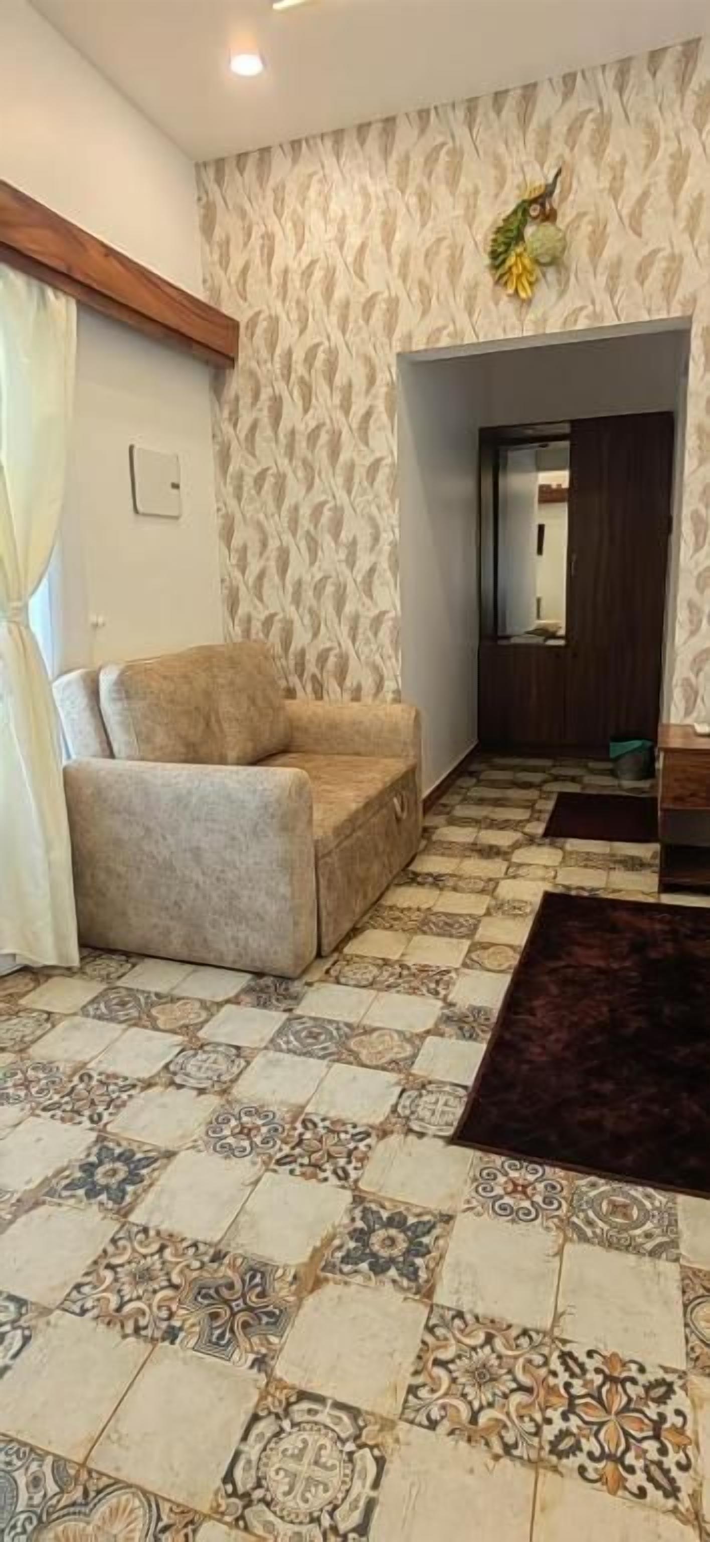 Sala de estar com ladrilhos estampados, um sofá, um tapete escuro e um espelho na parede.