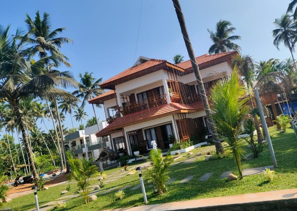 A two-story building with a red-tiled roof, surrounded by palm trees and a well-maintained lawn.