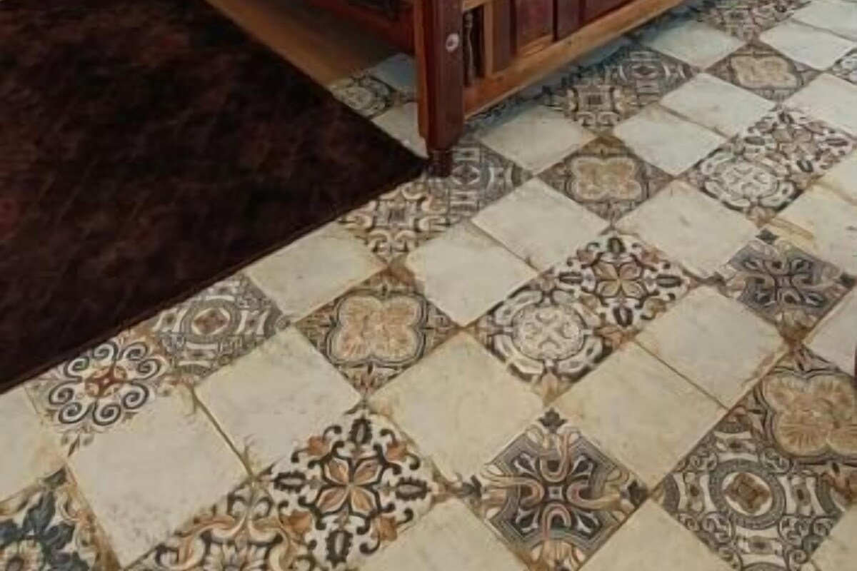 Un dormitorio con una cama de madera, papel tapiz estampado, un ventilador de techo y una alfombra decorativa.