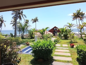 A resort with a paved pathway leading to a building, surrounded by palm trees and a view of the ocean. - Flower Hill Cottage (Varkala)