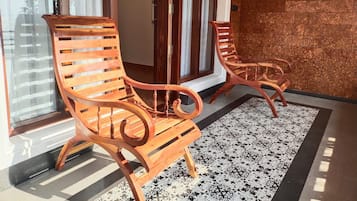 Duas cadeiras de madeira com encosto e apoio de braço curvos, sobre um piso estampado.