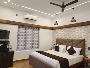 Una habitación de hotel con una cama, un escritorio, un televisor y un ventilador de techo.