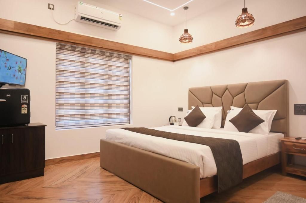 Un dormitorio con cama, televisor, ventana con persianas y equipo de aire acondicionado.