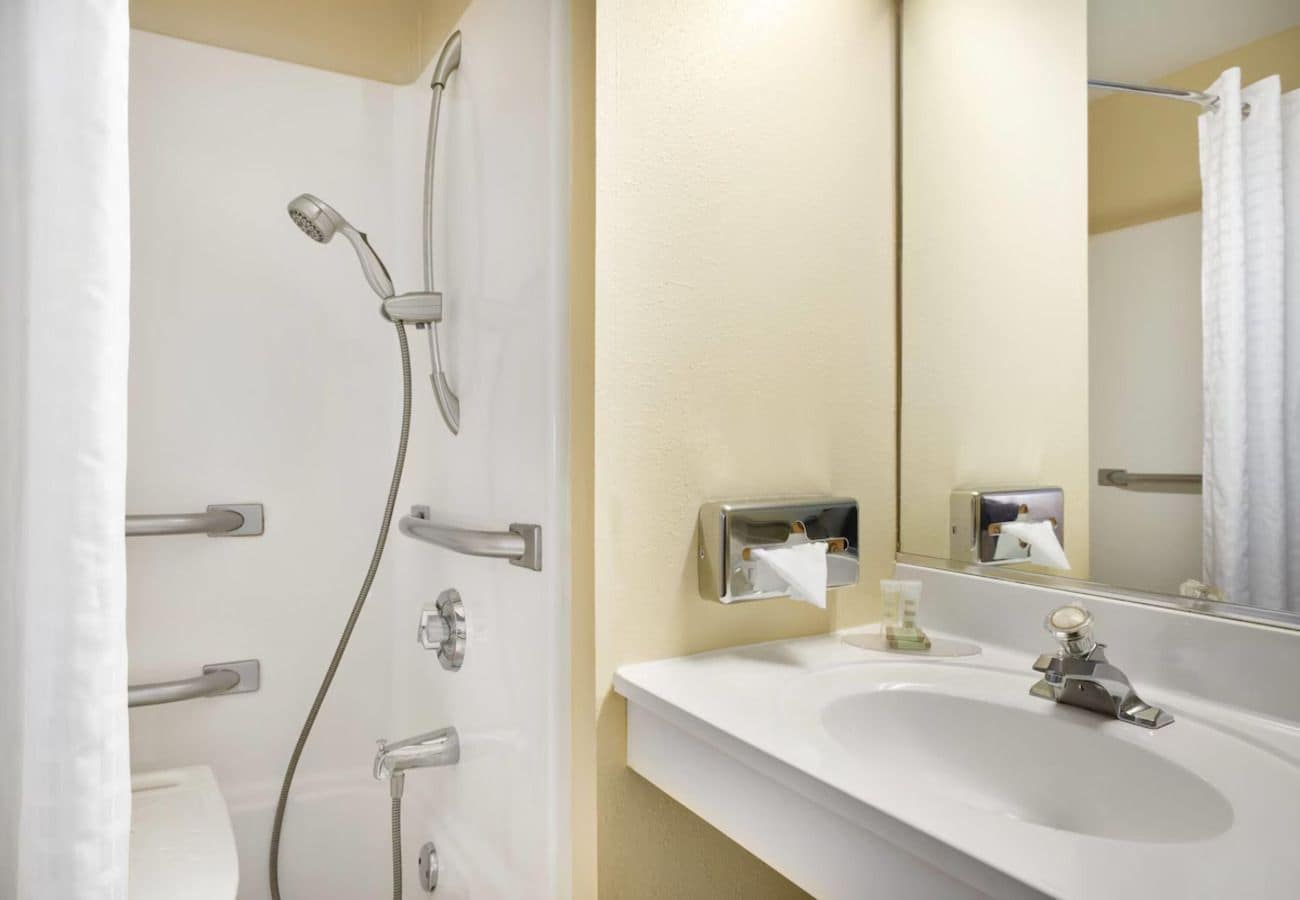 A bathroom with a shower, toilet, sink, and a mirror.