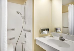 A bathroom with a shower, toilet, sink, and a mirror. - amerivu inn & suites alton (Alton)