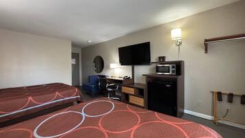 A hotel room with two beds, a desk, a chair, a television, a microwave, and a small refrigerator.