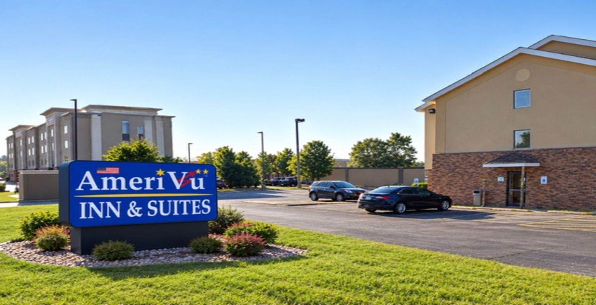 A hotel sign for AmeriVu Inn & Suites with a parking lot and buildings in the background.