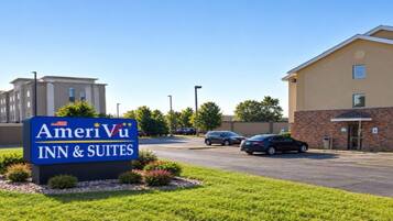 A hotel sign for AmeriVu Inn & Suites with a parking lot and buildings in the background.