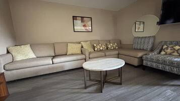 A living room with a sofa, a coffee table, and a TV mounted on the wall.