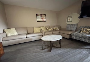 Un salon avec un canapé, une table basse et un téléviseur fixé au mur.