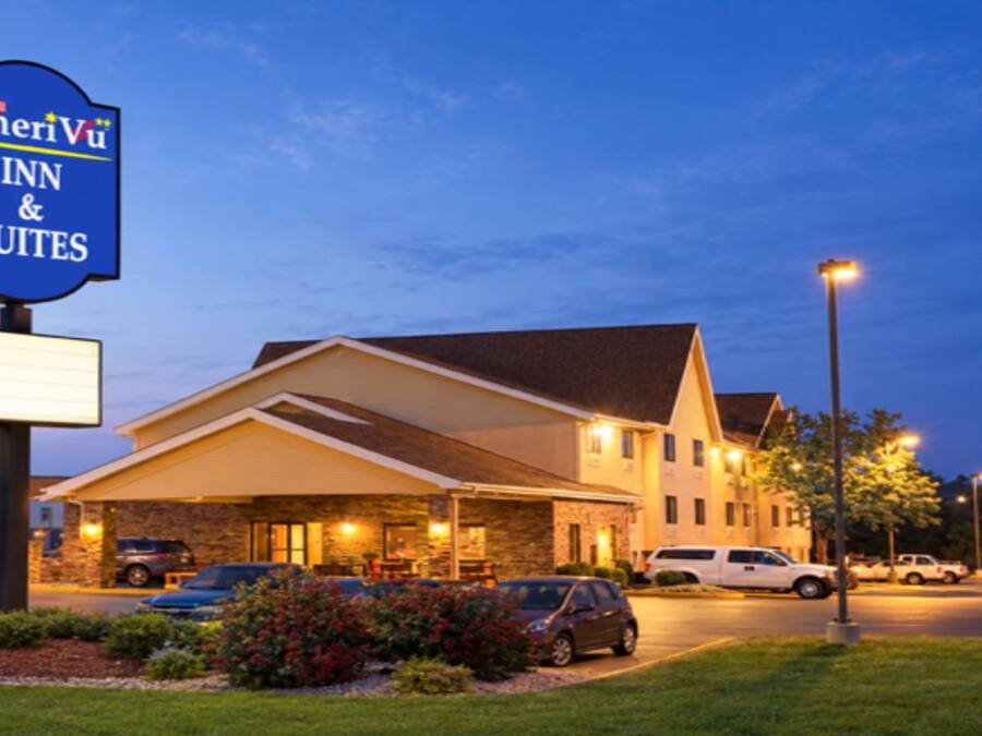 Un hotel con el letrero de AmeriViu Inn & Suites, un estacionamiento y una fachada de edificio bien iluminada.