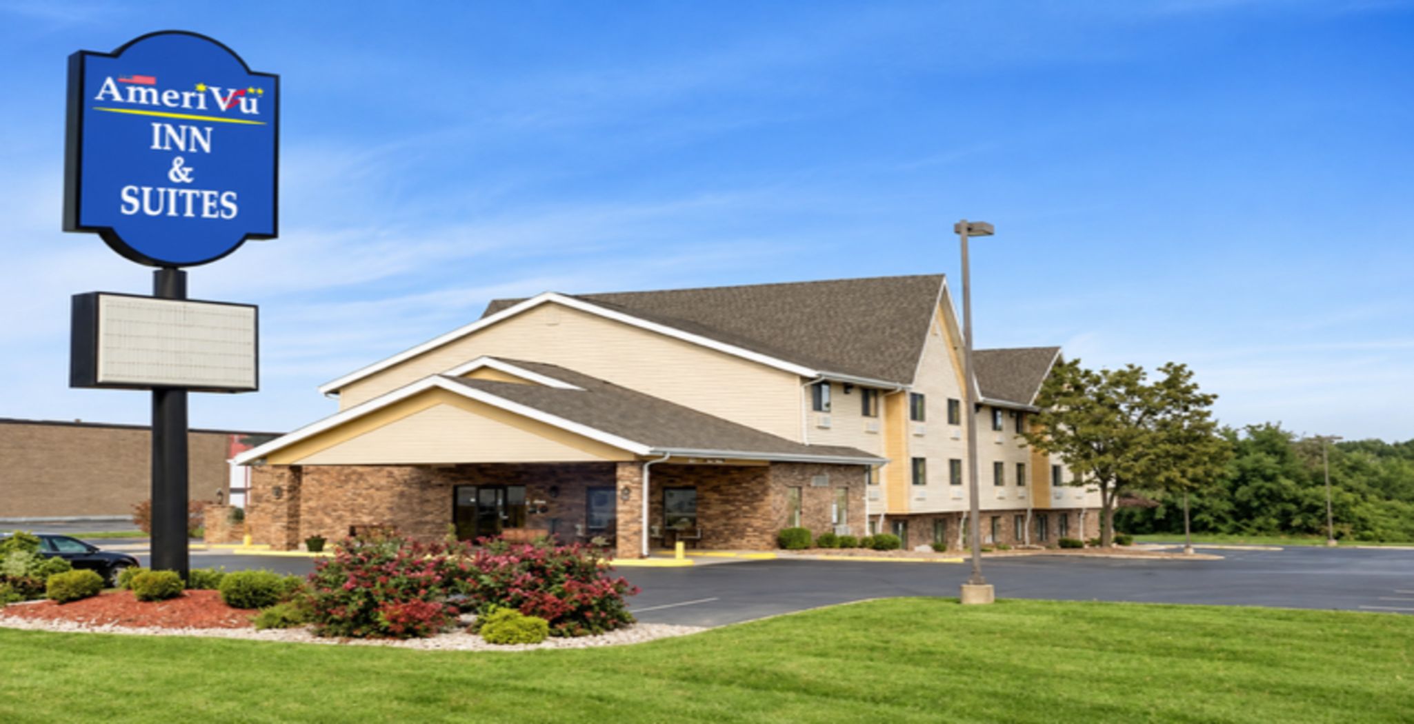 Een hotel met een bordje voor AmeriVu Inn & Suites, met een gevel van baksteen, een overdekte ingang en een parkeerplaats.