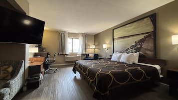 Habitación de hotel con una cama grande, un escritorio, una silla, un televisor y un cuadro en la pared.