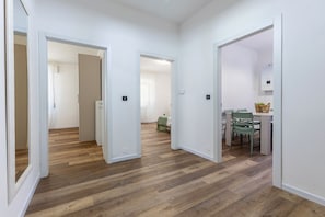 A hallway with wooden flooring leading to a dining area with chairs and a table. - A bright 96-square-meter apartment, perfect for seven people, located on the first floor of a building without an elevator.The property enjoys an ideal location for exploring the streets of the historic center—with its charming vistas, shops, and local (Ferrara)
