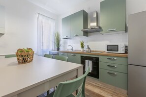 A modern kitchen with green cabinets, a microwave, and a dining area with a table and chairs. - A bright 96-square-meter apartment, perfect for seven people, located on the first floor of a building without an elevator.The property enjoys an ideal location for exploring the streets of the historic center—with its charming vistas, shops, and local (Ferrara)