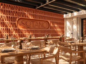 A restaurant interior with a wooden wall featuring the name 'SOTANO' and tables set for dining. - Casa Luma (Cape Town)