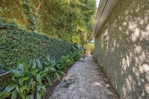 A narrow brick pathway flanked by lush greenery and a stone wall. - Great 3 bedroom 3 bath single story house near Pier/Village and the beach (Saint Simons Island)