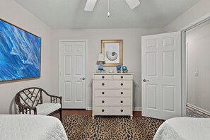 A bedroom with a bed, a chair, a dresser, a painting, and two doors. - Great 3 bedroom 3 bath single story house near Pier/Village and the beach (Saint Simons Island)
