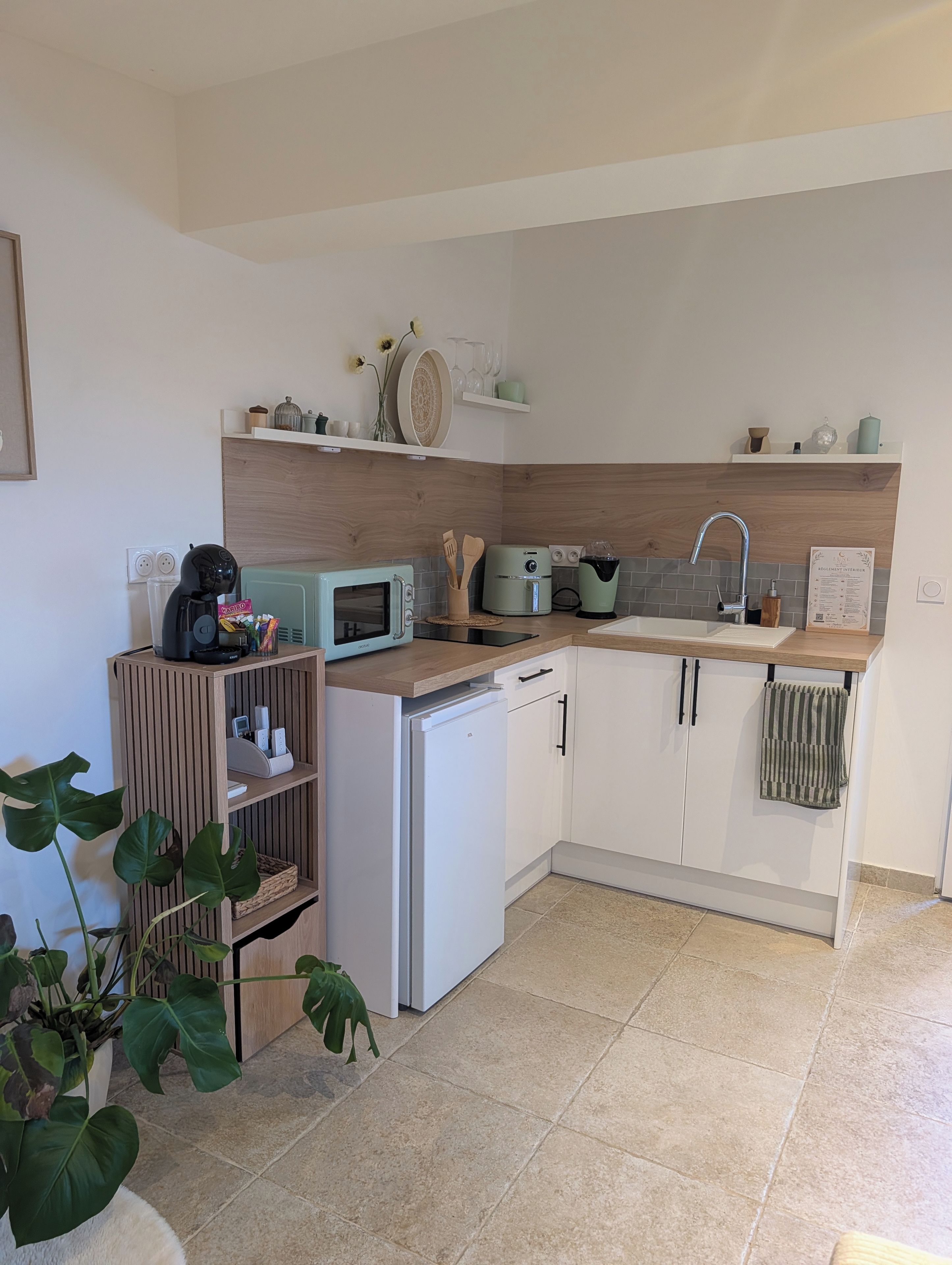 Eine moderne Küche mit Mikrowelle, Toaster und Wasserkocher auf der Arbeitsfläche, Holzausstattung und einem Spülbecken.
