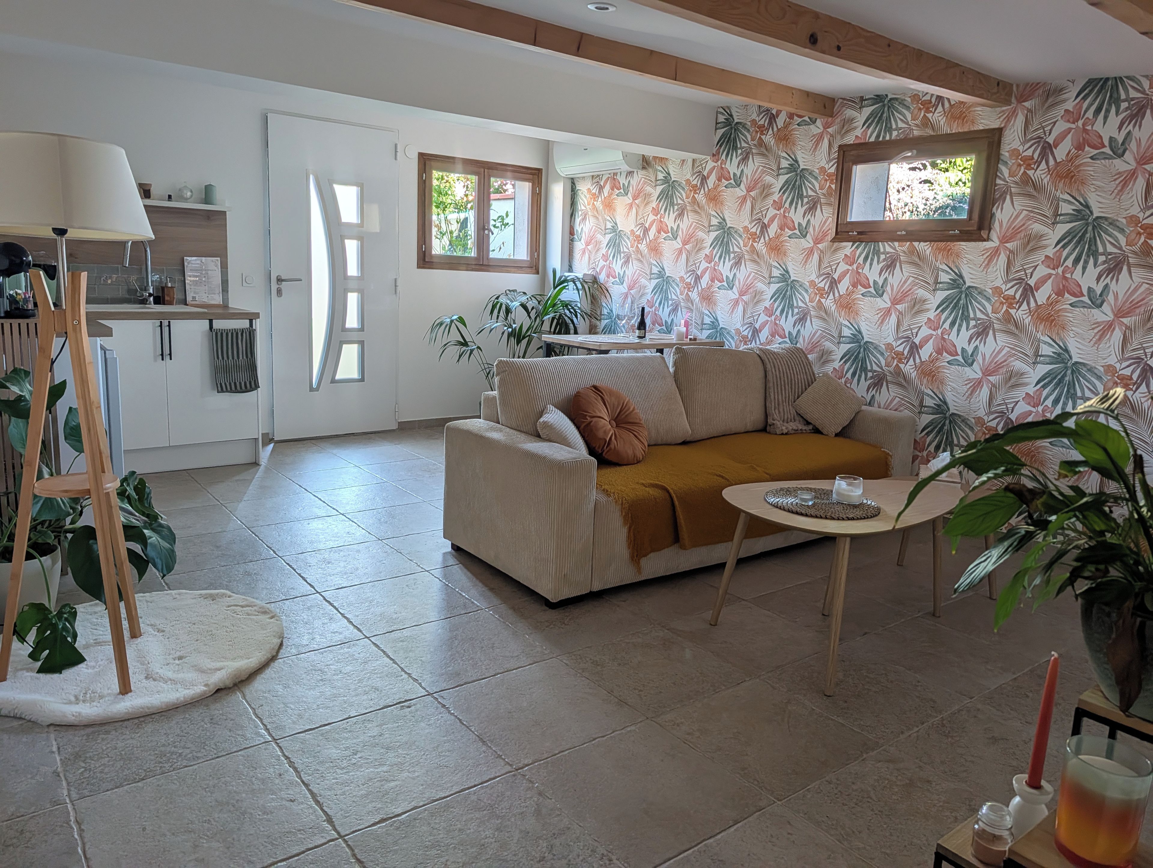 Ein Wohnzimmer mit einer Couch, einem kleinen Tisch und einer Küche im Hintergrund.