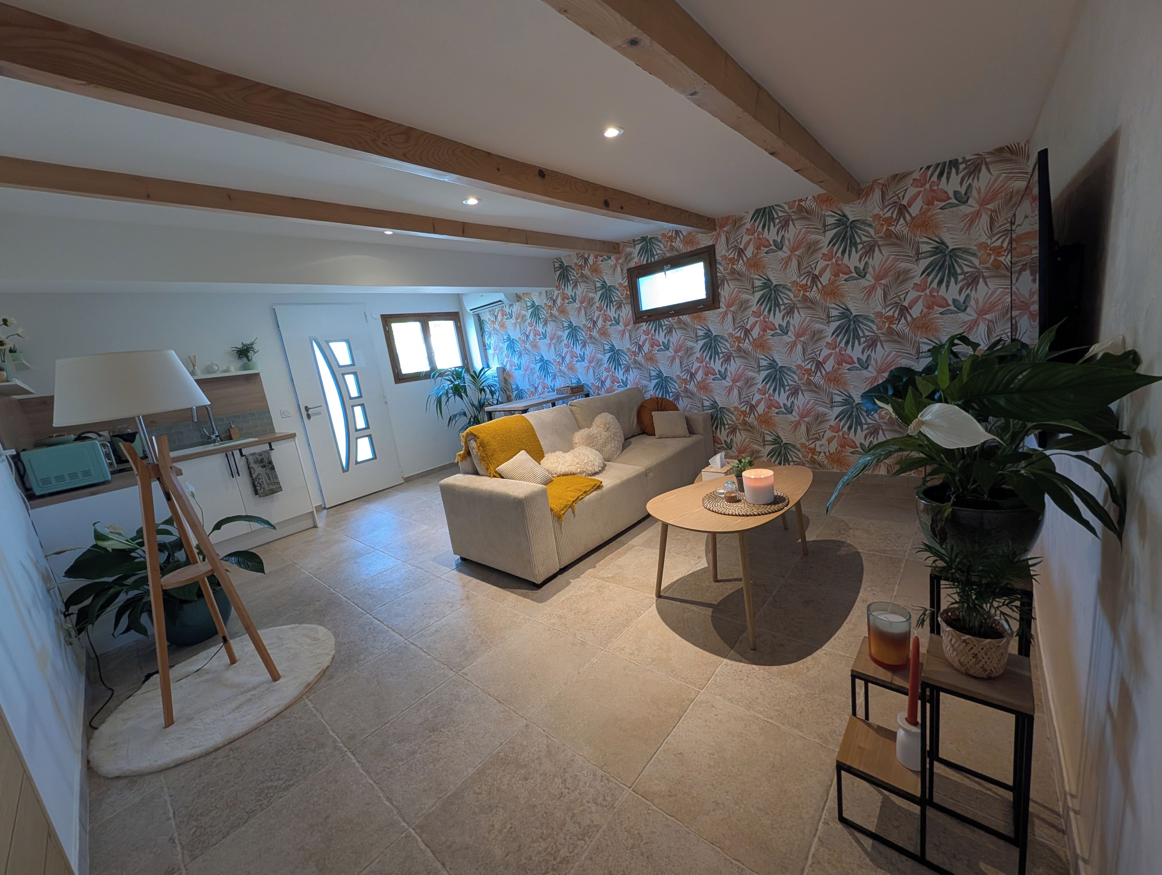 Ein Wohnzimmer mit einer Couch, einem Couchtisch, einer Lampe und einem an der Wand befestigten Fernseher.