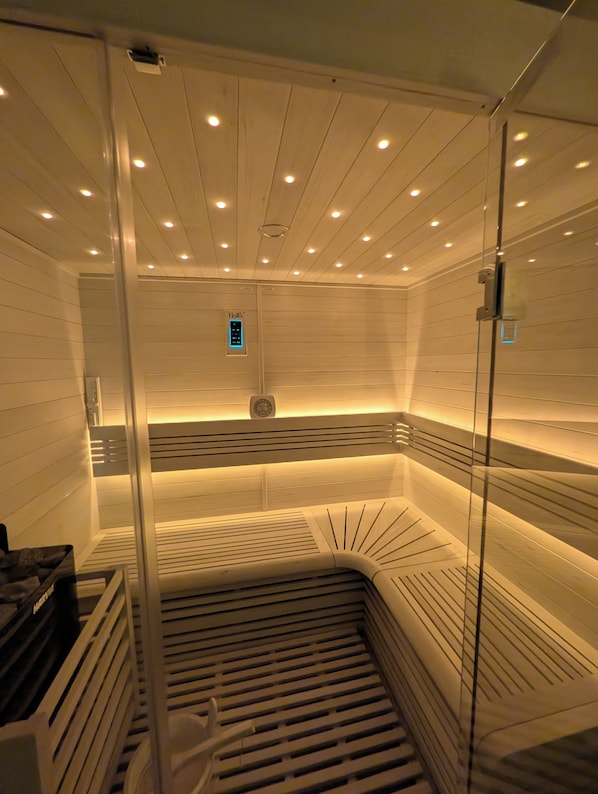 Un sauna avec des parois en lattes de bois, un banc et un panneau de commande.