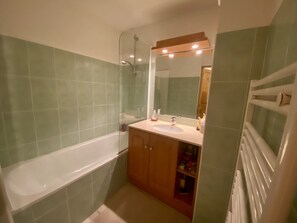 A bathroom with a bathtub, a sink, a mirror, and a shower. - A201 - 57 m² - 3-room apartment - 6 people (Prapoutel)