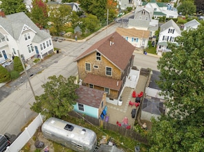 A residential area with a two-story house featuring a sloped roof, a fenced backyard with outdoor seating, and a parked trailer. - Perfect spacious and sunsoaked 4-bedroom house near beach in Old Orchard Beach (Old Orchard Beach)