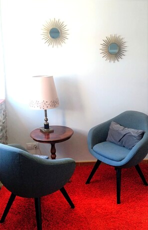 A room with two armchairs, a small table with a lamp, and two wall-mounted sunburst decorations. - Apartment in Fisterra (Fisterra)
