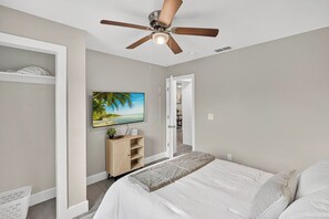 A bedroom with a bed, a ceiling fan, a TV on the wall, and a door leading to another room. - Aesthetic 3BR Home w/ Coffee Bar & Large Yard (Abilene)