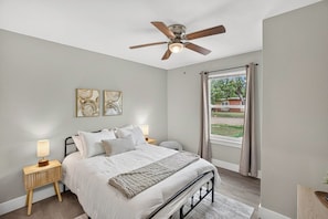 Ein Schlafzimmer mit einem Bett, Nachttischlampen, einem Deckenventilator und Kunstwerken an der Wand.