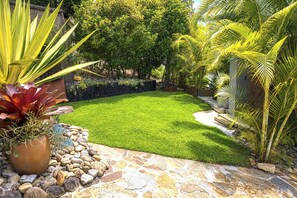 Un jardín bien cuidado con una variedad de plantas, un sendero de piedra y un césped ordenado.