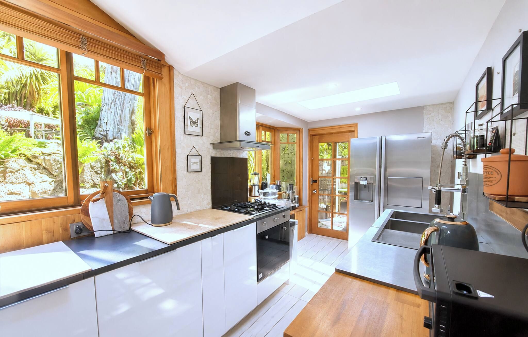 A modern kitchen with a gas stove, stainless steel appliances, and a view of greenery outside.