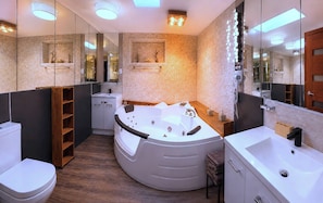 Un baño moderno con una bañera independiente, un espejo grande y un tocador con lavabo.