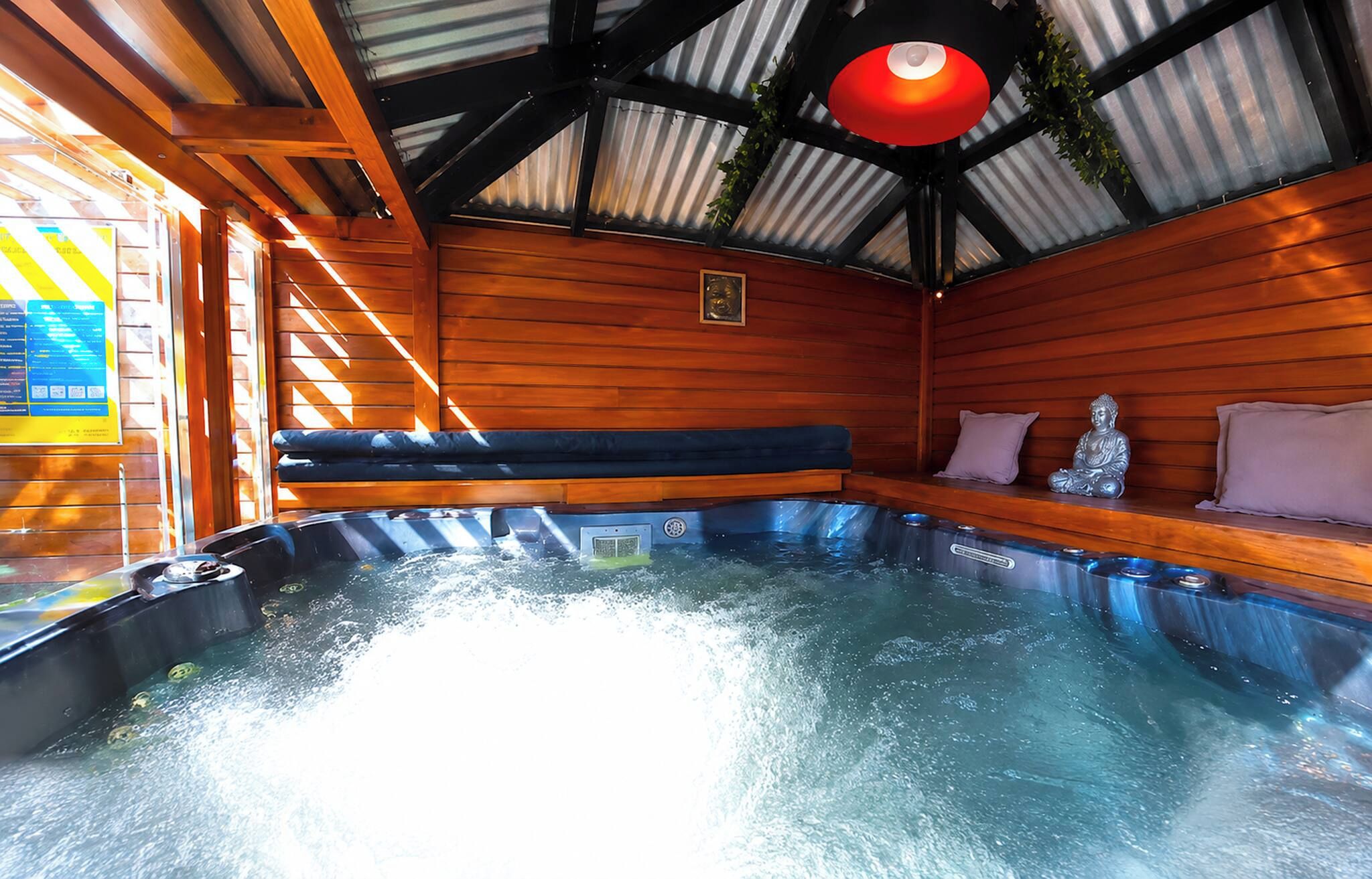Un bain à remous avec des parois en bois et un plafond recouvert de panneaux métalliques.