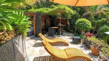 Une terrasse avec un banc en bois, un espace barbecue et des plantes en pot.