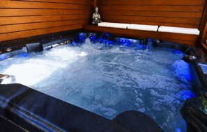 Un jacuzzi con interior de madera y una estatua de Buda.