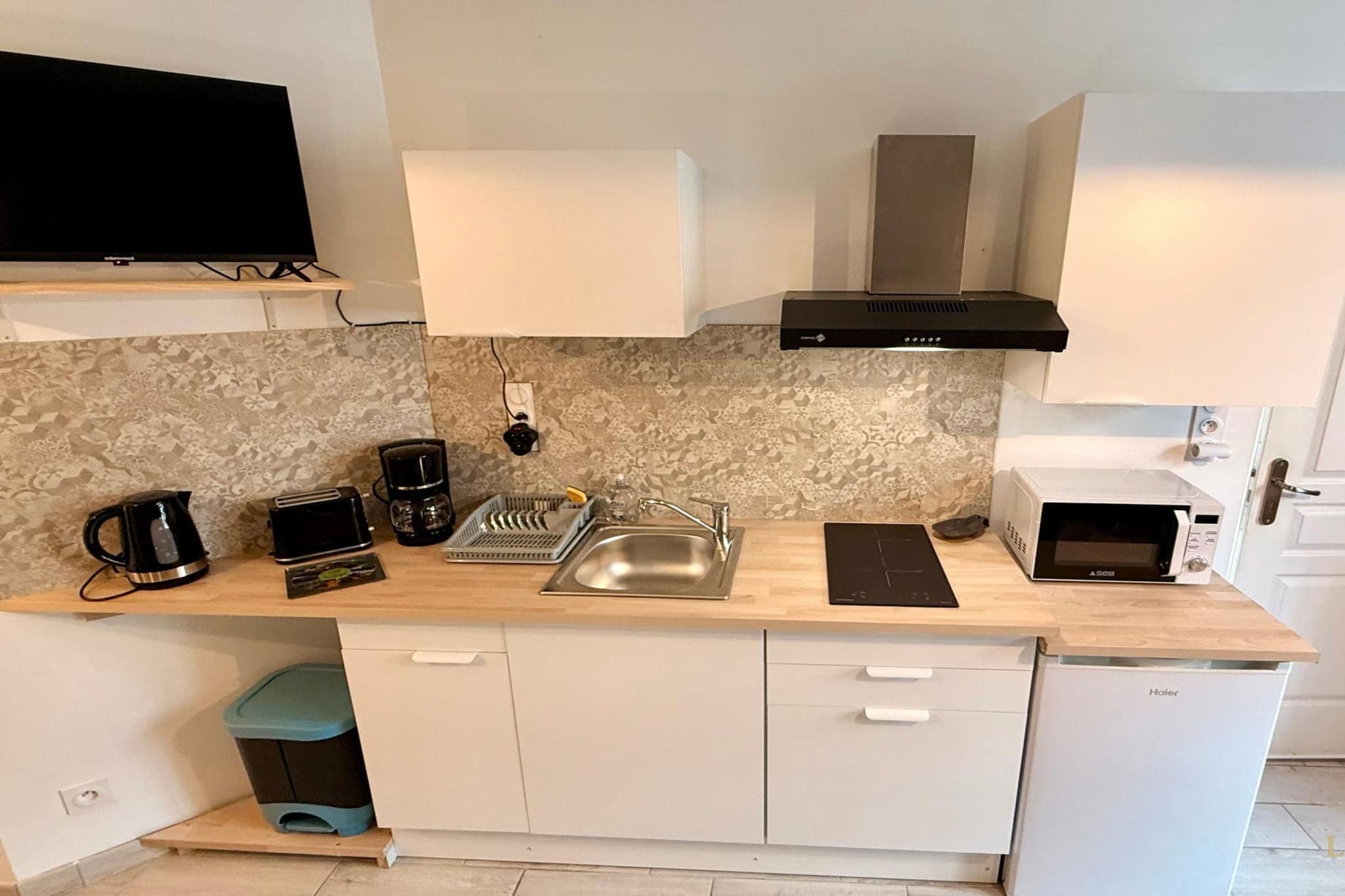 A compact kitchen with a microwave, toaster, coffee maker, and a sink.