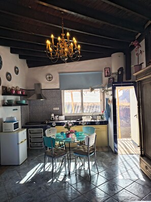 A kitchen with a dining area, a chandelier, and a view of the outdoors. - Country House 'Finca Fani 1 con Estudio' with Sea and Mountain Views, Pool, Wi-Fi, Terrace and Garden (Los Corralillos)