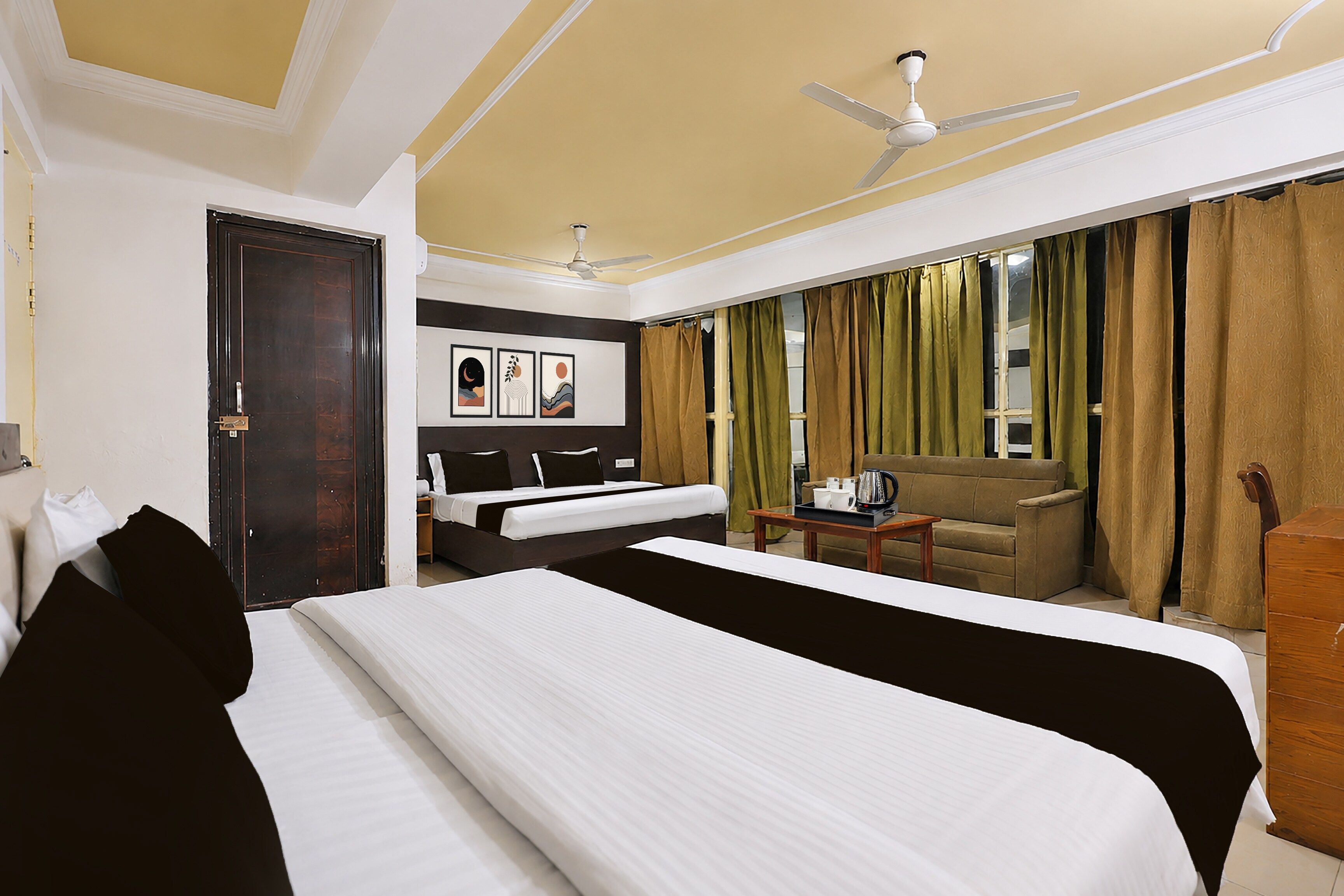 A hotel room with a large bed, a desk with a coffee maker, a sofa, and a view of the outdoors.