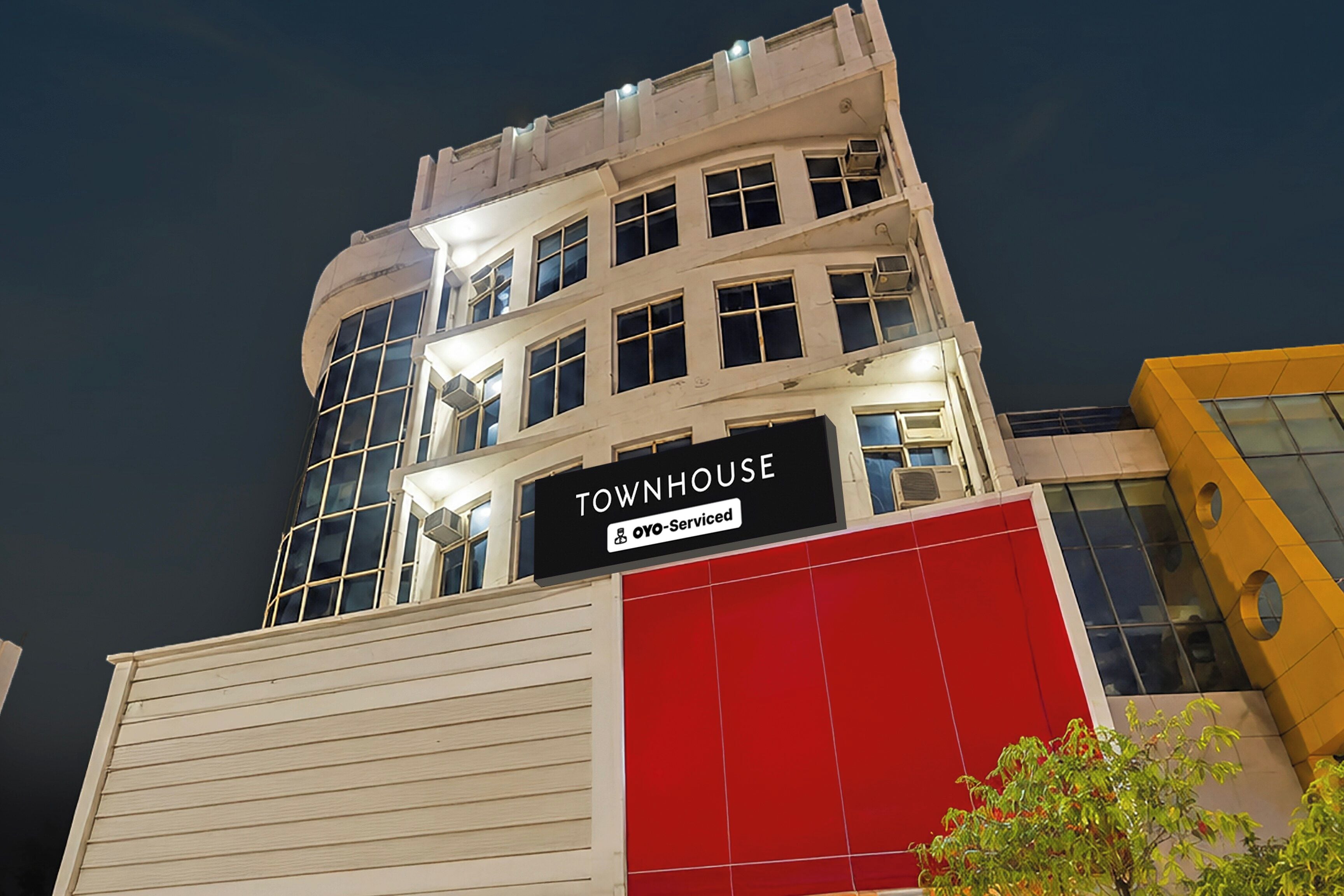 A multi-story building with a sign reading 'TOWNHOUSE' and 'OYO-Serviced'.