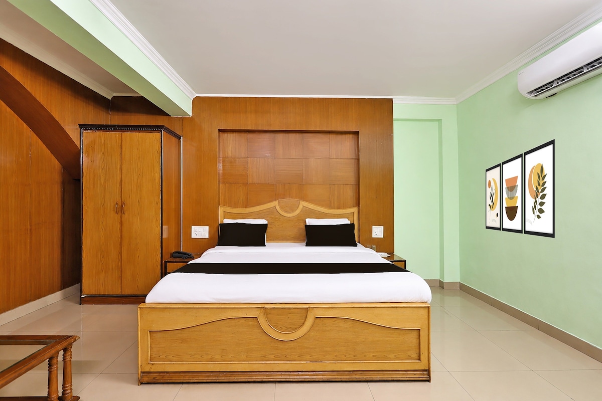 A hotel room with a large bed, wooden headboard, and a wardrobe.