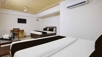 Una habitación de hotel con cama, escritorio con cafetera, una silla y aire acondicionado.