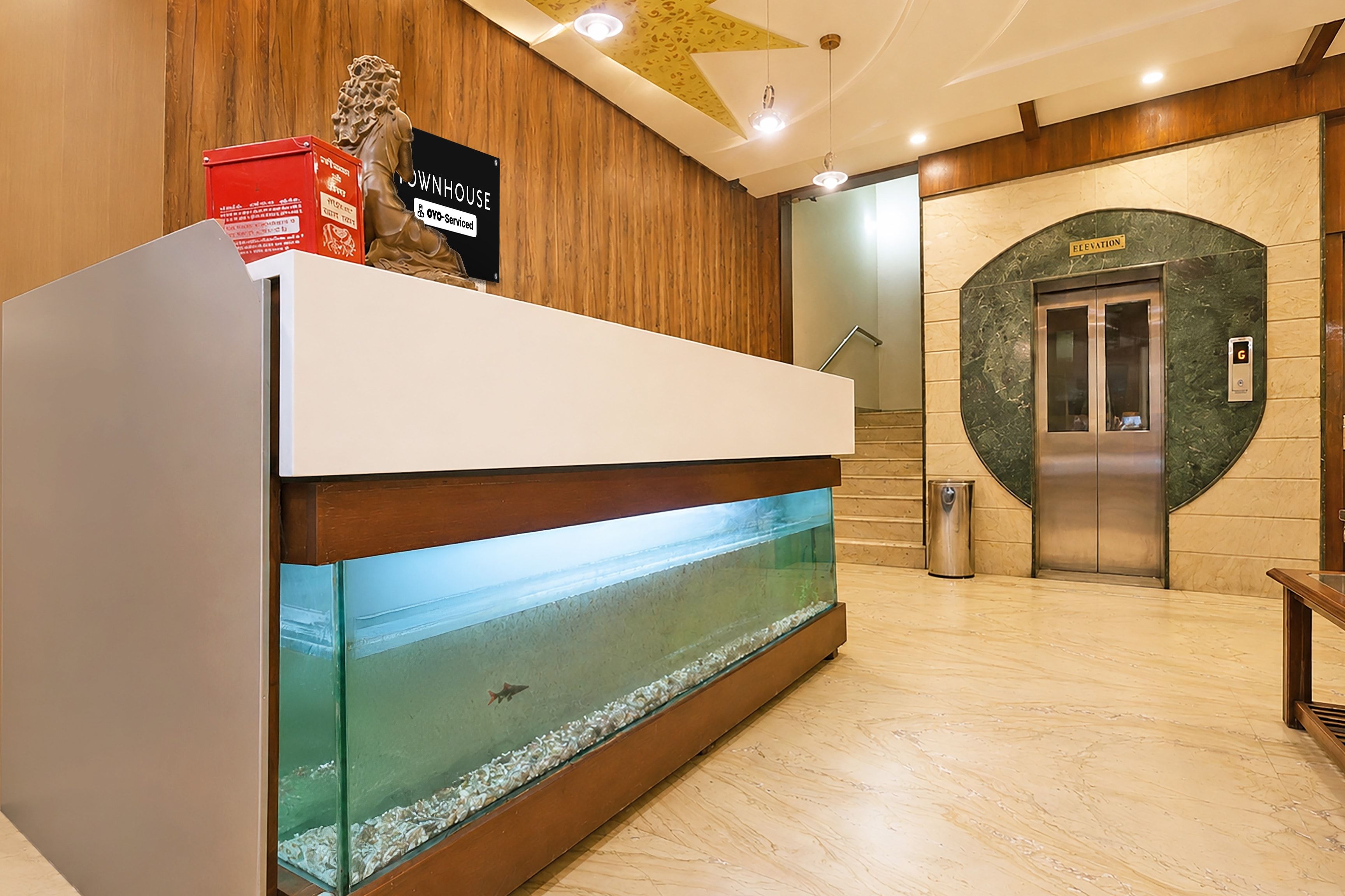 A reception desk with a fish tank, a lion statue, and a sign indicating the house is serviced by OVO.