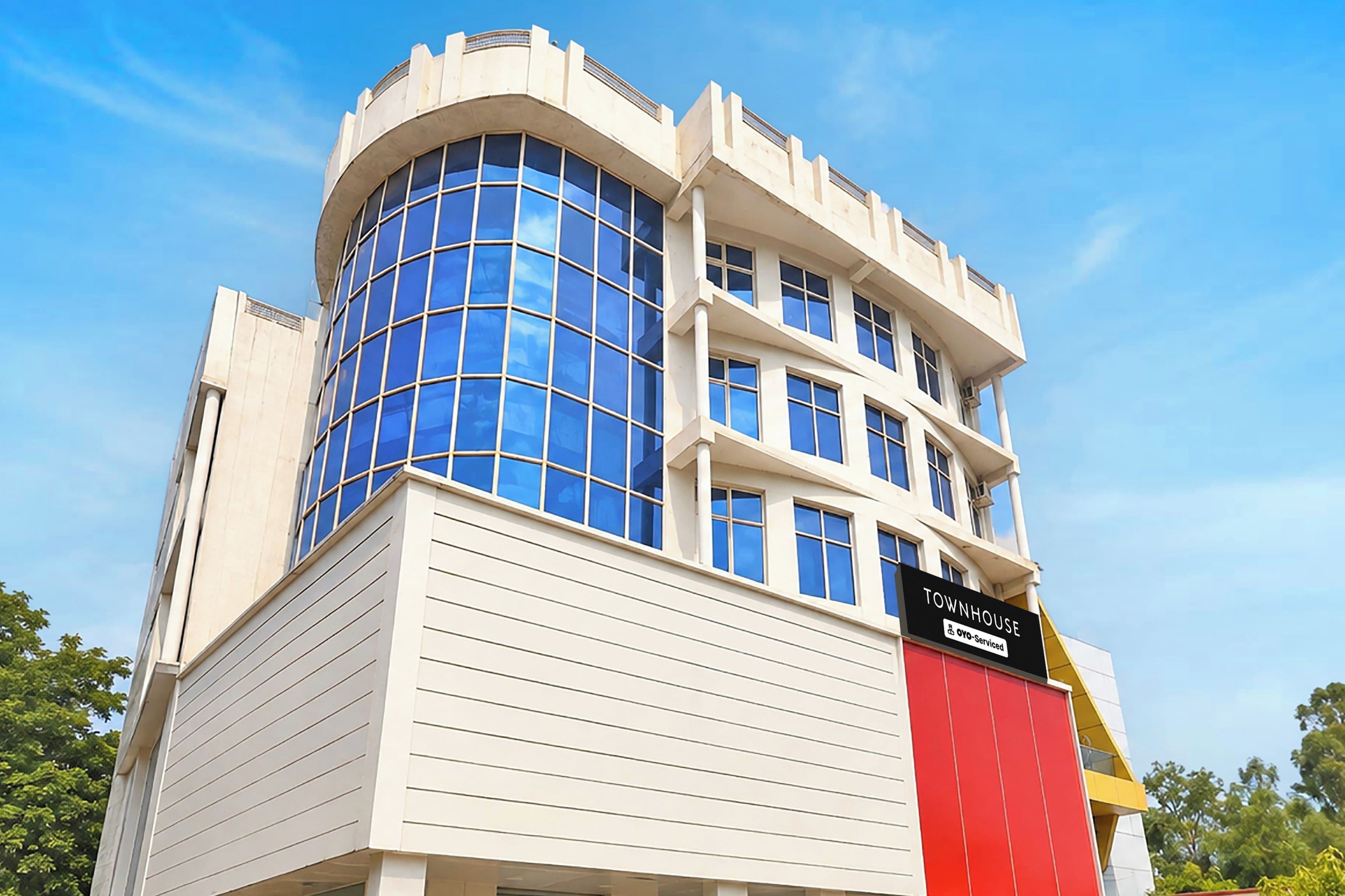 A multi-story building with a curved glass facade and a sign indicating it is serviced by a specific company.