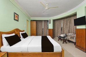 A hotel room with a bed, a ceiling fan, a television, curtains, and a coffee table. - Townhouse City Centre Gwalior (Gwalior)